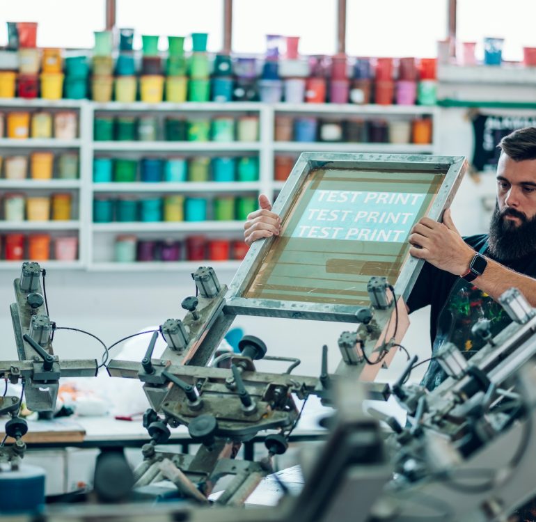 Male worker preparing screen printing film in a workshop Male worker preparing screen printing film in a workshop